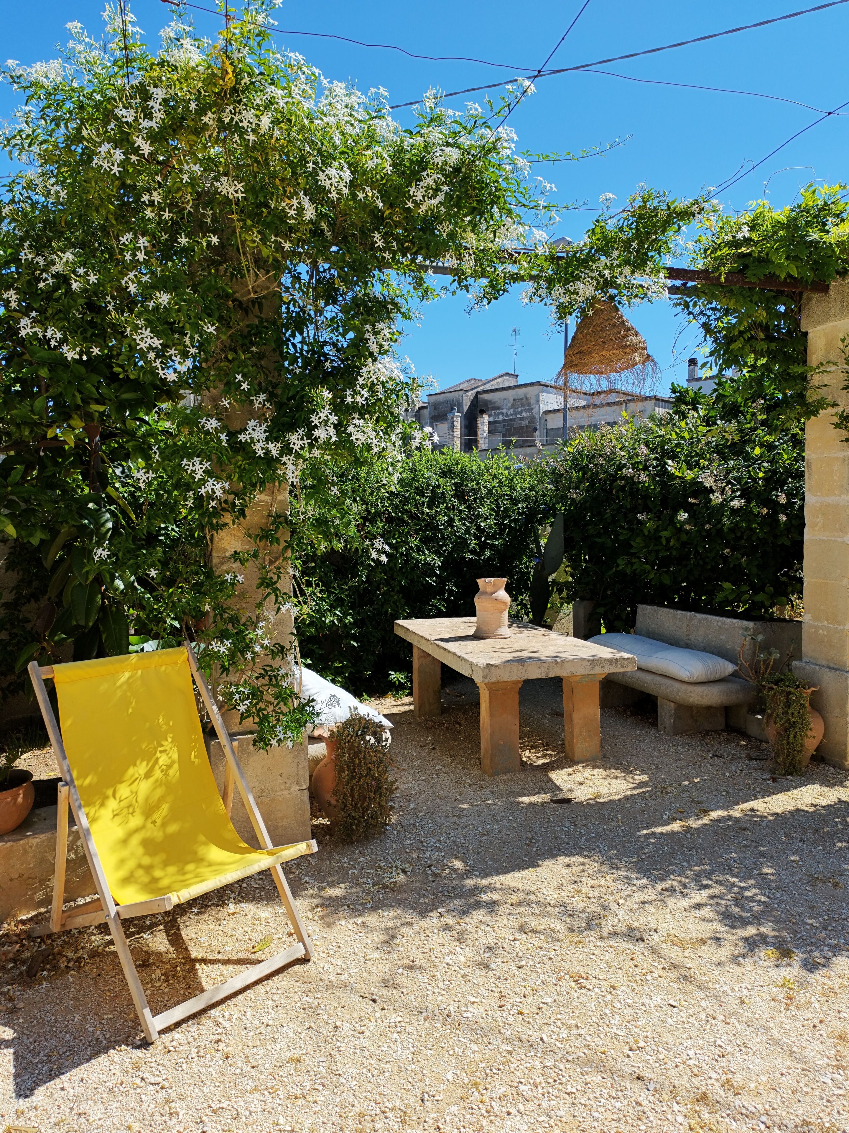 Un patio jardín con una silla amarilla, una mesa y un banco.