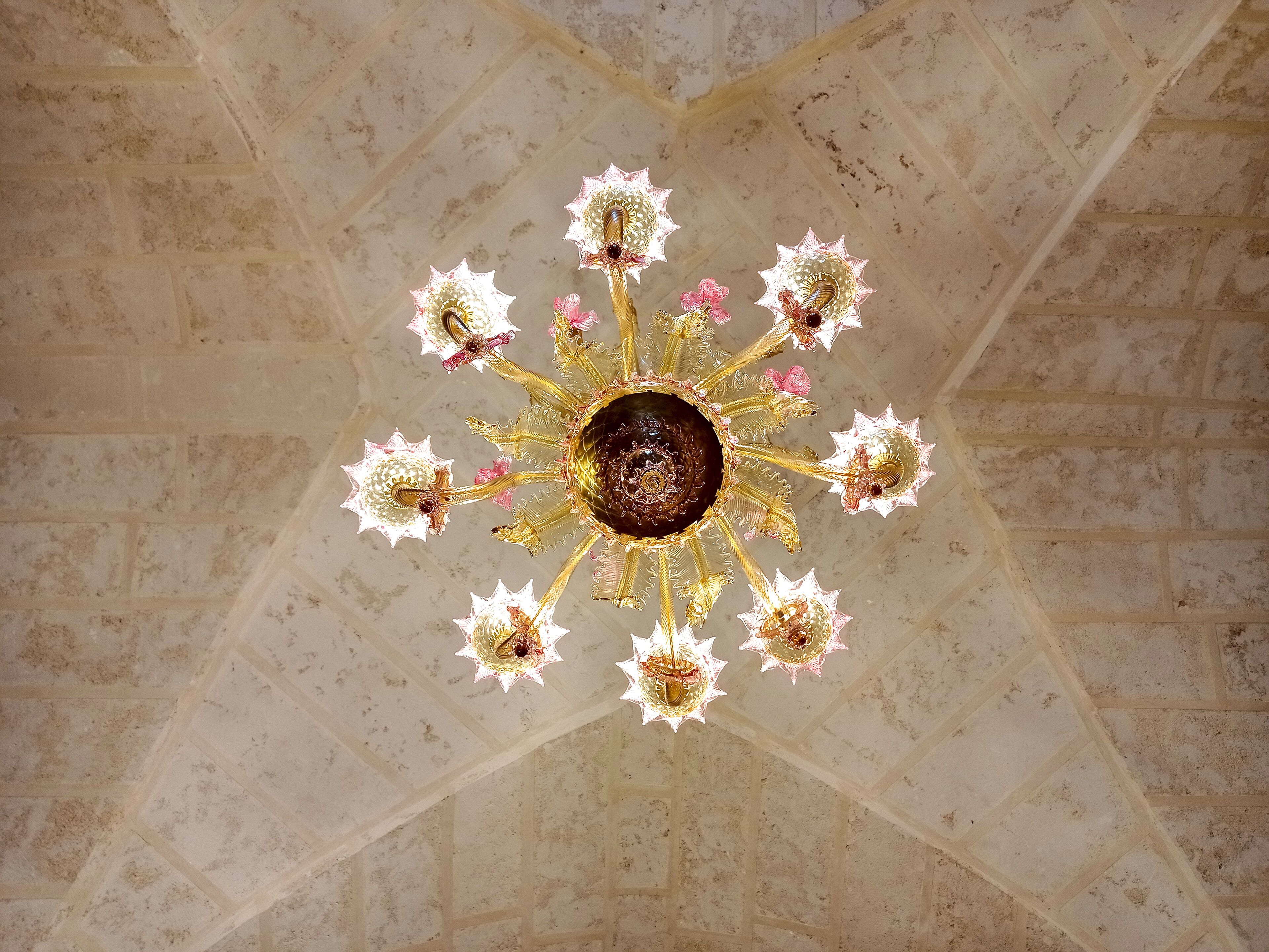 Ein Kronleuchter mit einer dunklen, zentralen Kugel und mehreren, floral verzierten Armen.