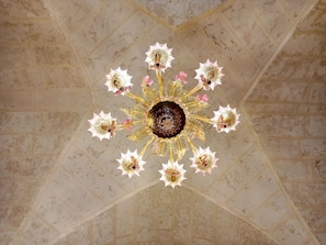 A chandelier with a central dark sphere and multiple arms with floral designs. - Giardino Frannicola (Maglie)