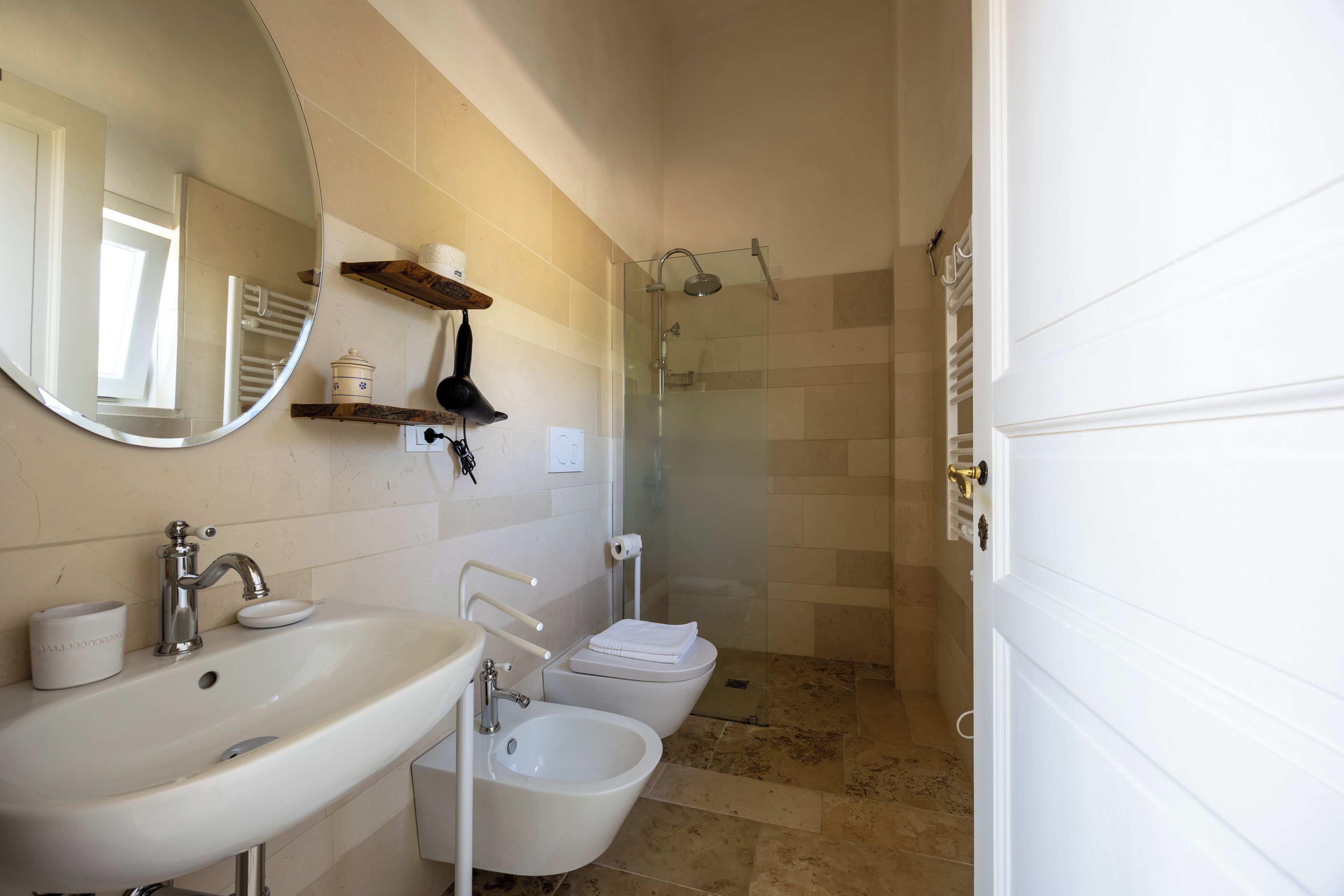 Een badkamer met een wastafel, bidet en douchecabine met glazen wanden.