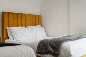 A bed with a wooden headboard, white bedding, and a grey blanket.
