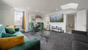 Uma sala de estar moderna com sofá, mesa de centro de vidro e área de jantar com cadeiras.