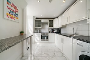 A modern kitchen with white cabinetry, a granite countertop, and a stainless steel dishwasher.