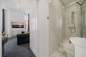 A modern bathroom with a glass-enclosed shower, a white toilet, and a marble-tiled floor. - Oxford Street Apartments 3, Charming Three Bedroom (London)