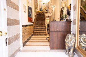 A hotel lobby with a marble staircase, a reception desk, and a lion statue. - Oxford Street Apartments 3, Charming Three Bedroom (London)