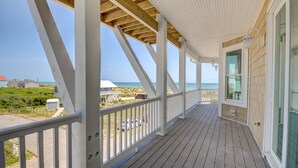 Una terraza cubierta de madera con vista al océano y casas de playa.