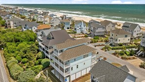 A coastal residential area with houses, a beach, and a clear sky. - Ocean Sounds: Spacious 7BR oceanview beach house in North Topsail with ocean views! (North Topsail Beach)