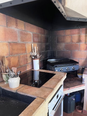 A kitchen with a gas stove, a sink, and a brick wall.