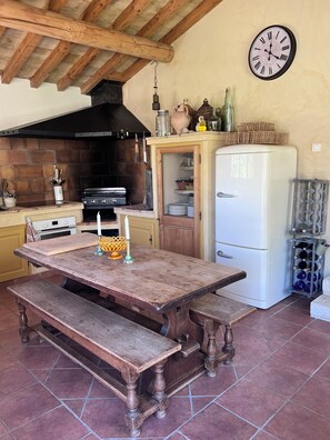 Een landelijke keuken met een houten tafel, een bank en een witte koelkast.