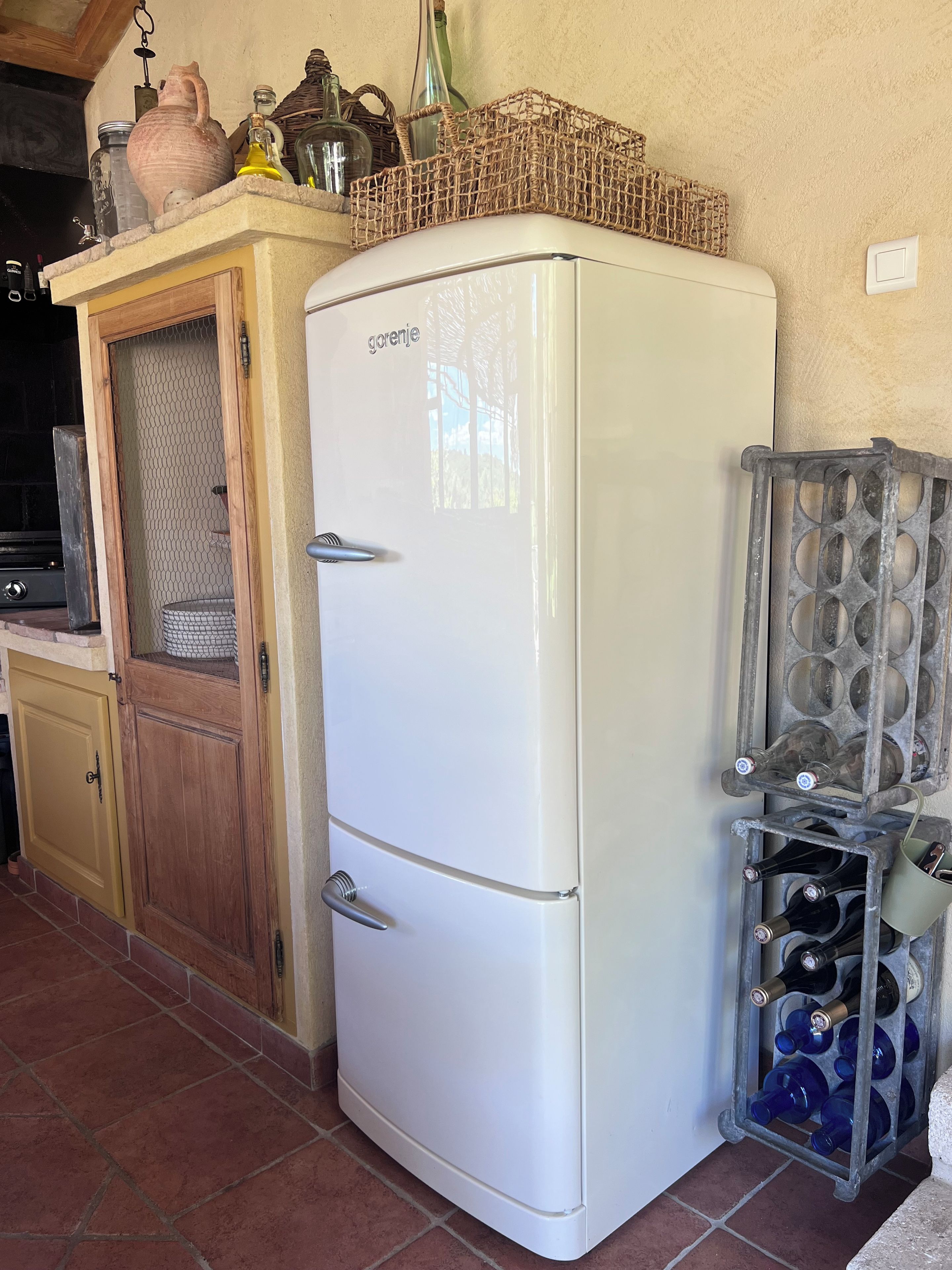 Una cocina con un refrigerador blanco, gabinetes de madera y una cava de vinos.