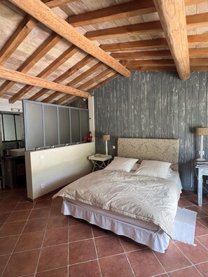 Een slaapkamer met een groot bed, een nachtkastje, een spiegel en een raam.