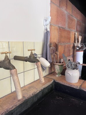 Een keuken met twee kraan, een handdoekhouder en een bestekhouder.