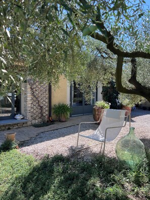 A patio area with a stone wall, potted plants, and a metal chair.