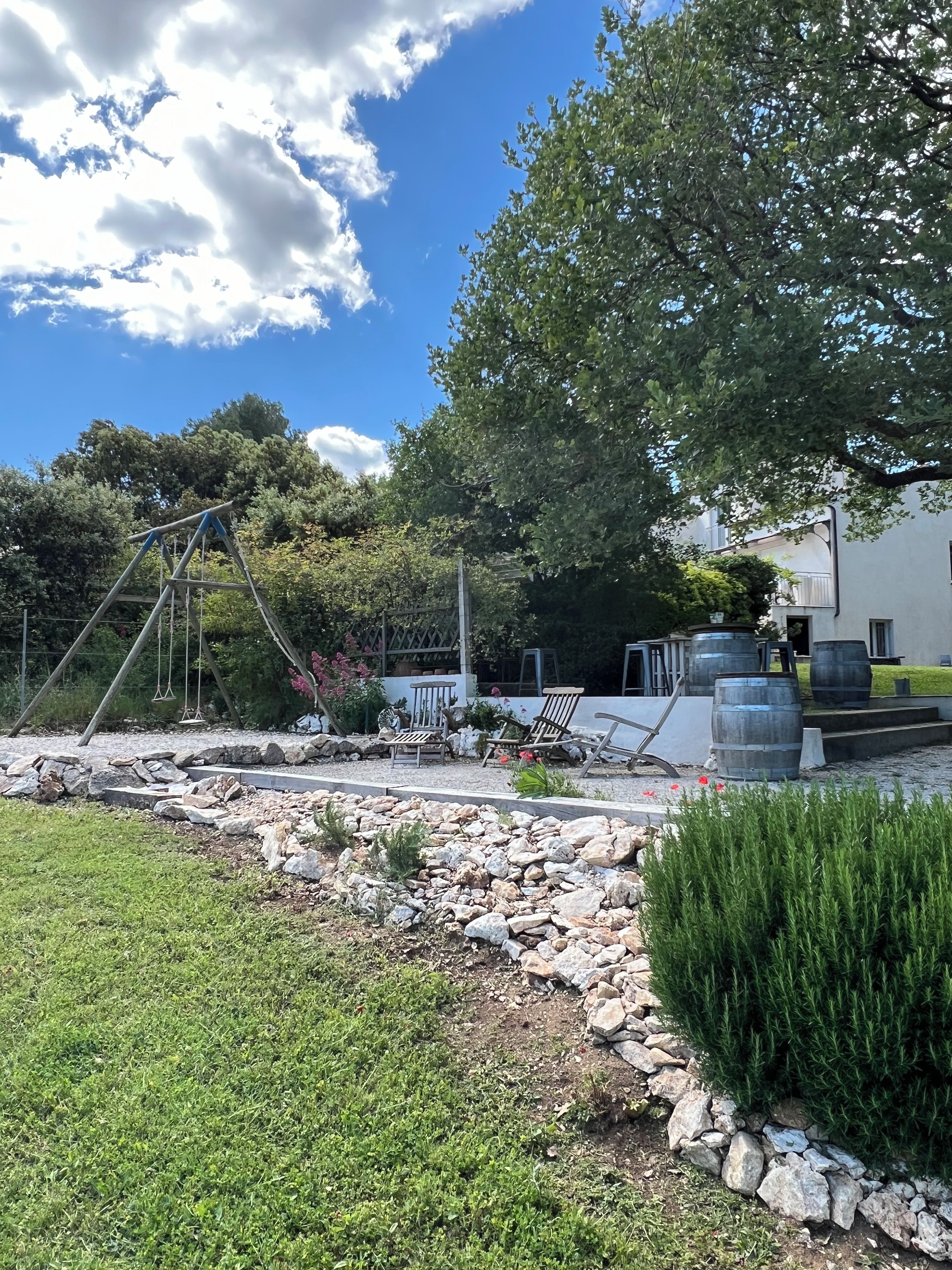 A garden with a swing set, seating area, and stone pathway.