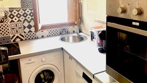 A compact kitchen with a washing machine, a sink, and an oven.
