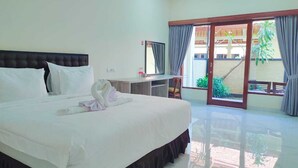 Una camera d'albergo con un letto grande, una scrivania e un balcone con tende.