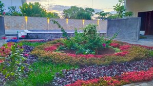 Un giardino curato con diverse piante e fiori, un muro in pietra e una scala che conduce a un livello superiore.