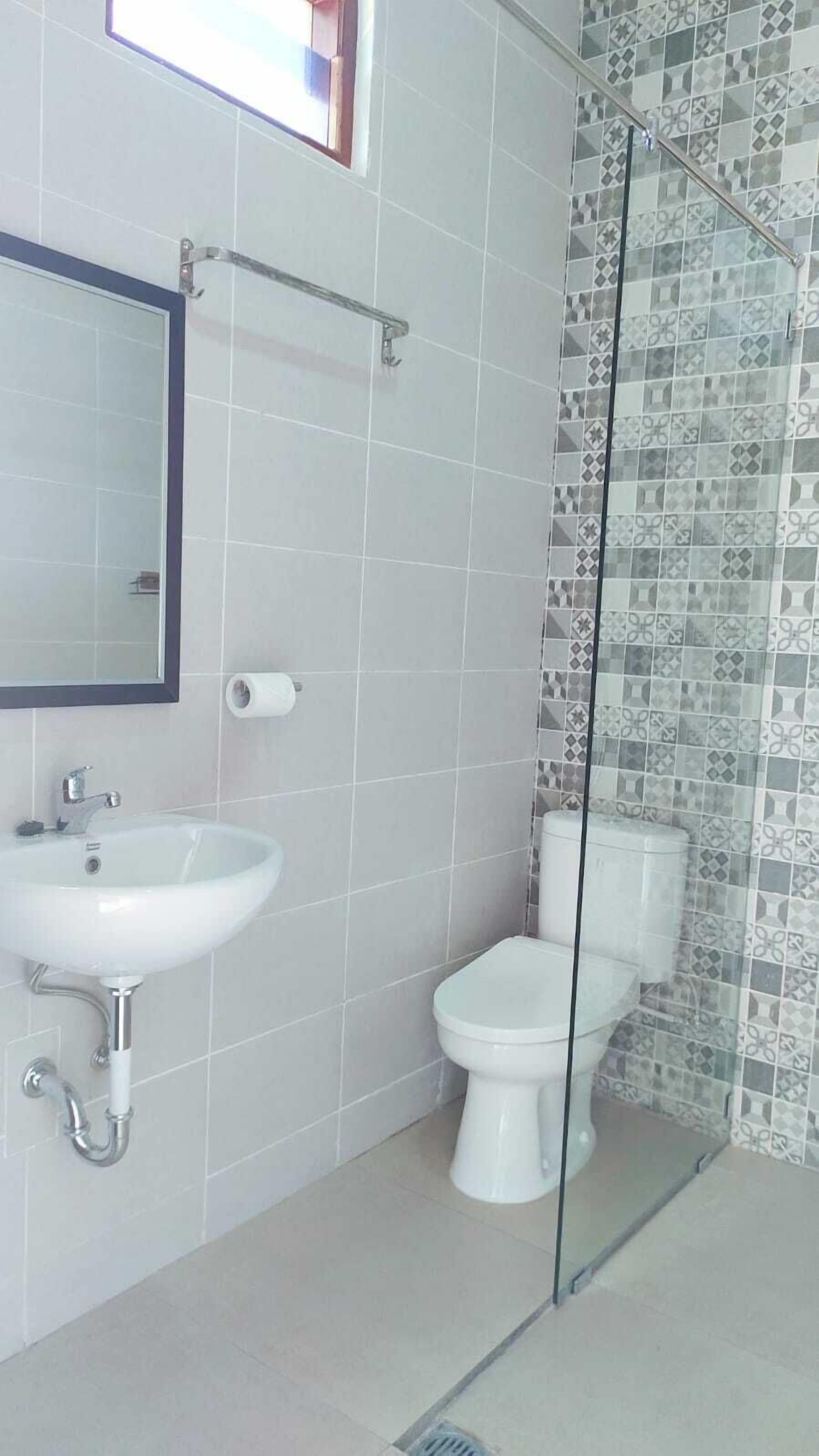 A bathroom with a white sink, a toilet, and a shower with patterned tiles.