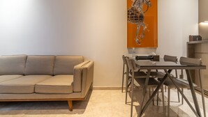 A modern living room with a beige sofa, a glass dining table, and a minimalist decor. - The Rixx Skyline Apartment on 21st floor- Netflix, D1, pool, gym, sauna, jacuzzi (Thành phố Hồ Chí Minh)