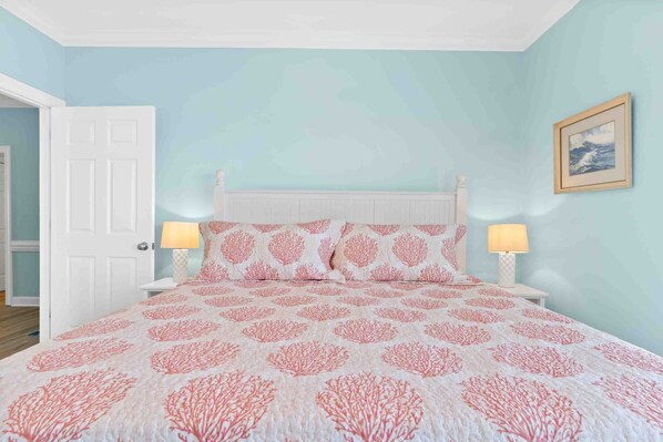 Une chambre à coucher avec un lit, deux lampes de chevet, une porte et un tableau encadré au mur.