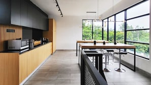 A modern kitchen with wooden cabinets, a built-in microwave, and a large window overlooking greenery. - Cabin15 -syariah (Blitar)