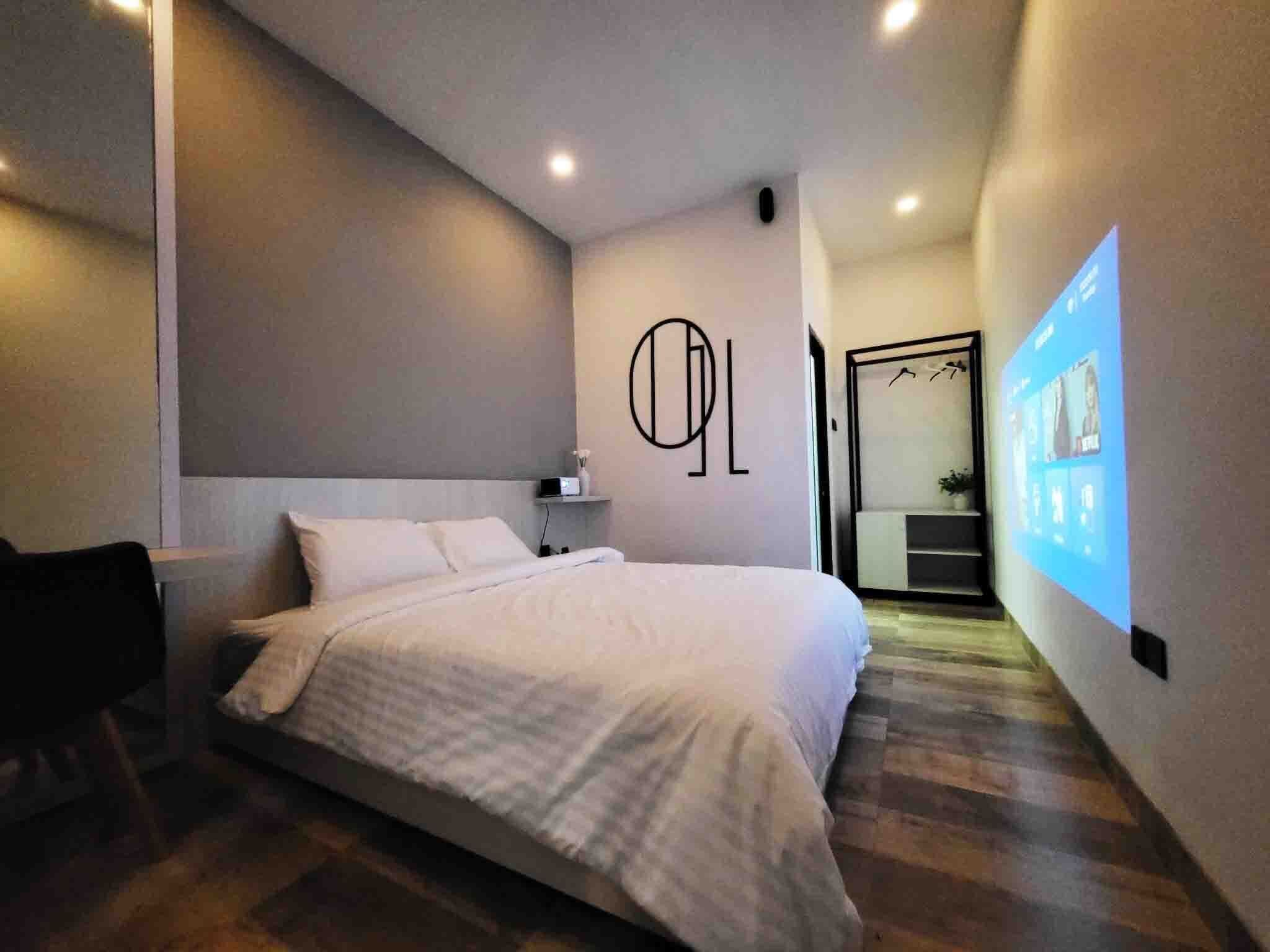 A modern hotel room with a large bed, a bedside table, and a wall-mounted TV.