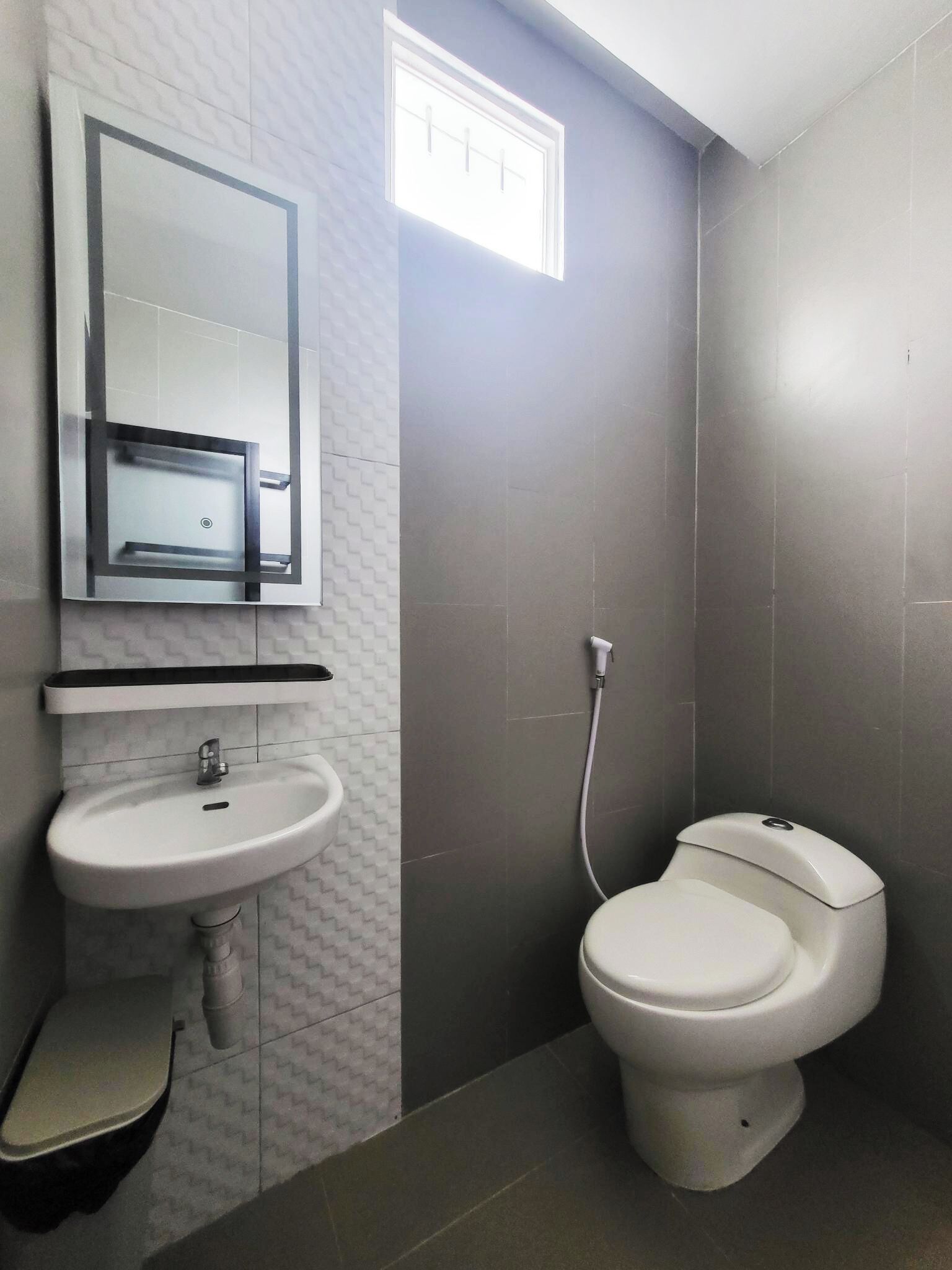 A bathroom with a white sink, mirror, and toilet.