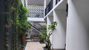 A modern building with a central corridor lined with plants and a patterned floor. - Cabin15 -syariah (Blitar)