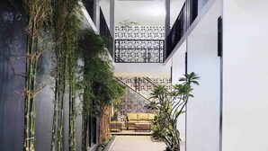 A modern building with a tiled walkway, bamboo plants, and a sofa in the center. - Cabin15 -syariah (Blitar)