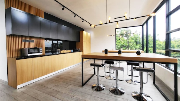 A modern kitchen with a wooden countertop, black cabinets, and a large window offering a view of greenery. - Cabin15 -syariah (Blitar)