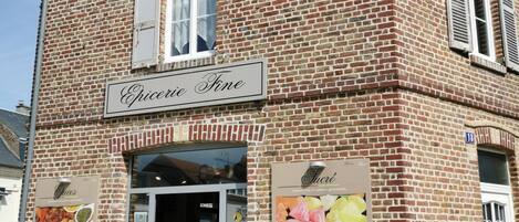 A brick building with a sign reading 'Epicurie Fine' and a display of colorful items outside.