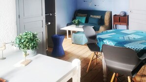 A room with a bed, a table, a chair, a potted plant, and a ceiling fan.