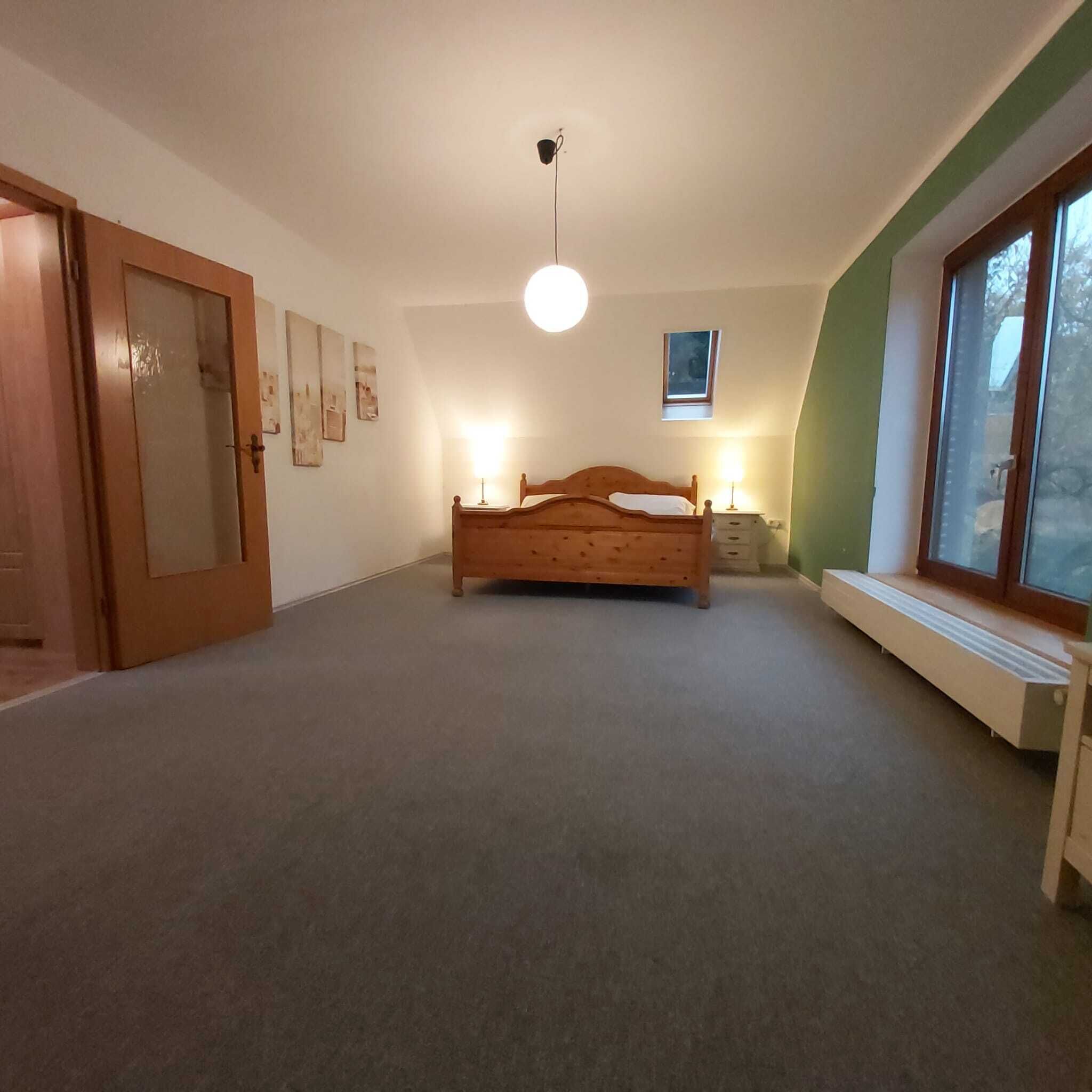 Un dormitorio con una cama de madera, una ventana y una lámpara en el techo.