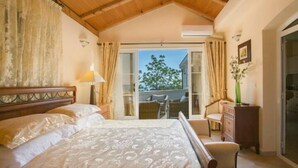A bedroom with a large bed, a wooden headboard, a nightstand, a dresser, and a view of the outside through a sliding glass door.