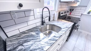 A modern kitchen with a granite countertop, stainless steel sink, and black faucet.