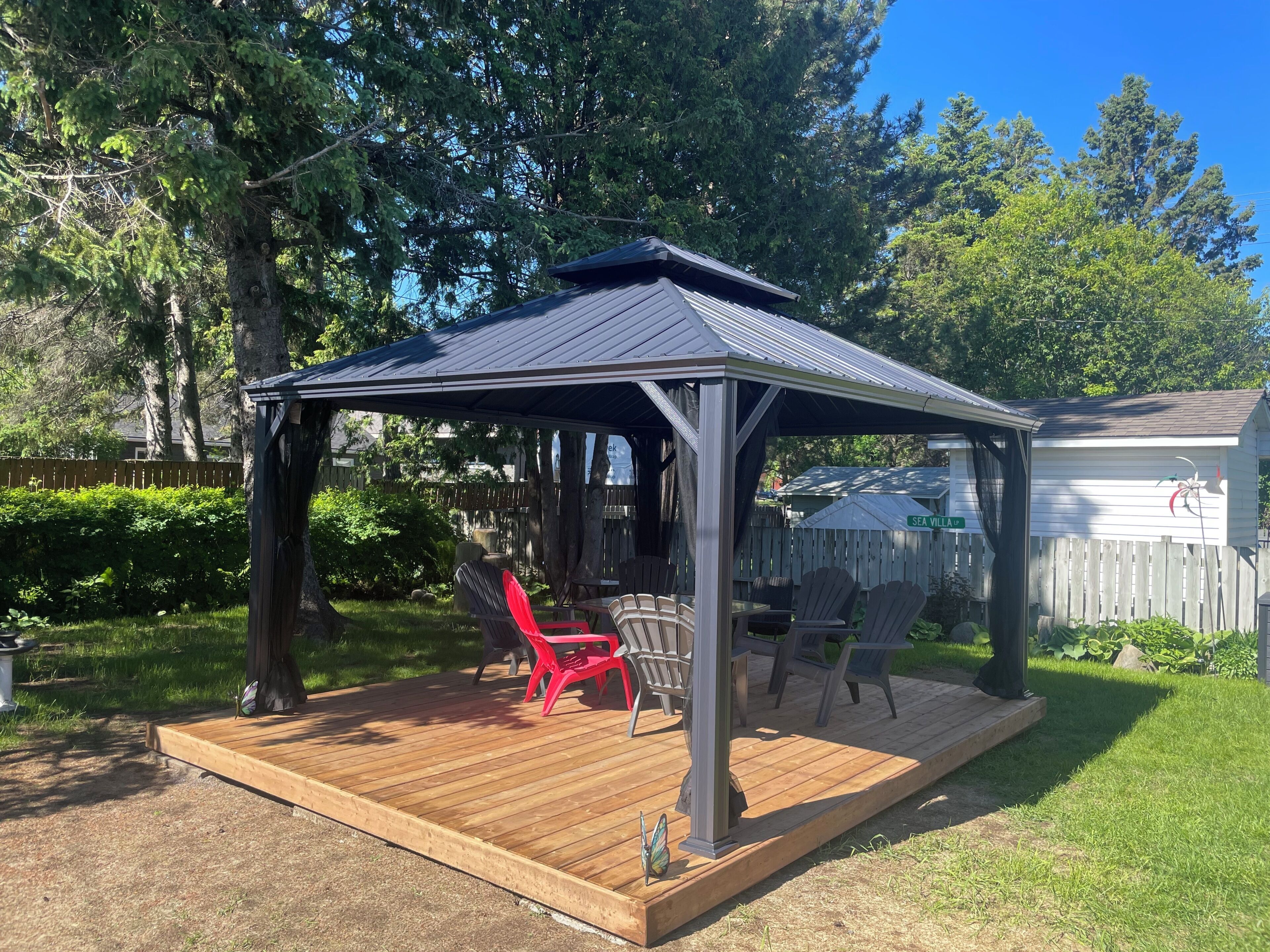 Un patio couvert doté d’une terrasse en bois, de mobilier d’extérieur et d’une structure en forme de pergola.
