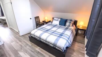 A bedroom with a large bed, two bedside tables with lamps, a wooden chair, and a wardrobe.