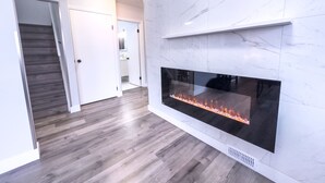 A modern interior with a fireplace, wooden flooring, and a staircase.