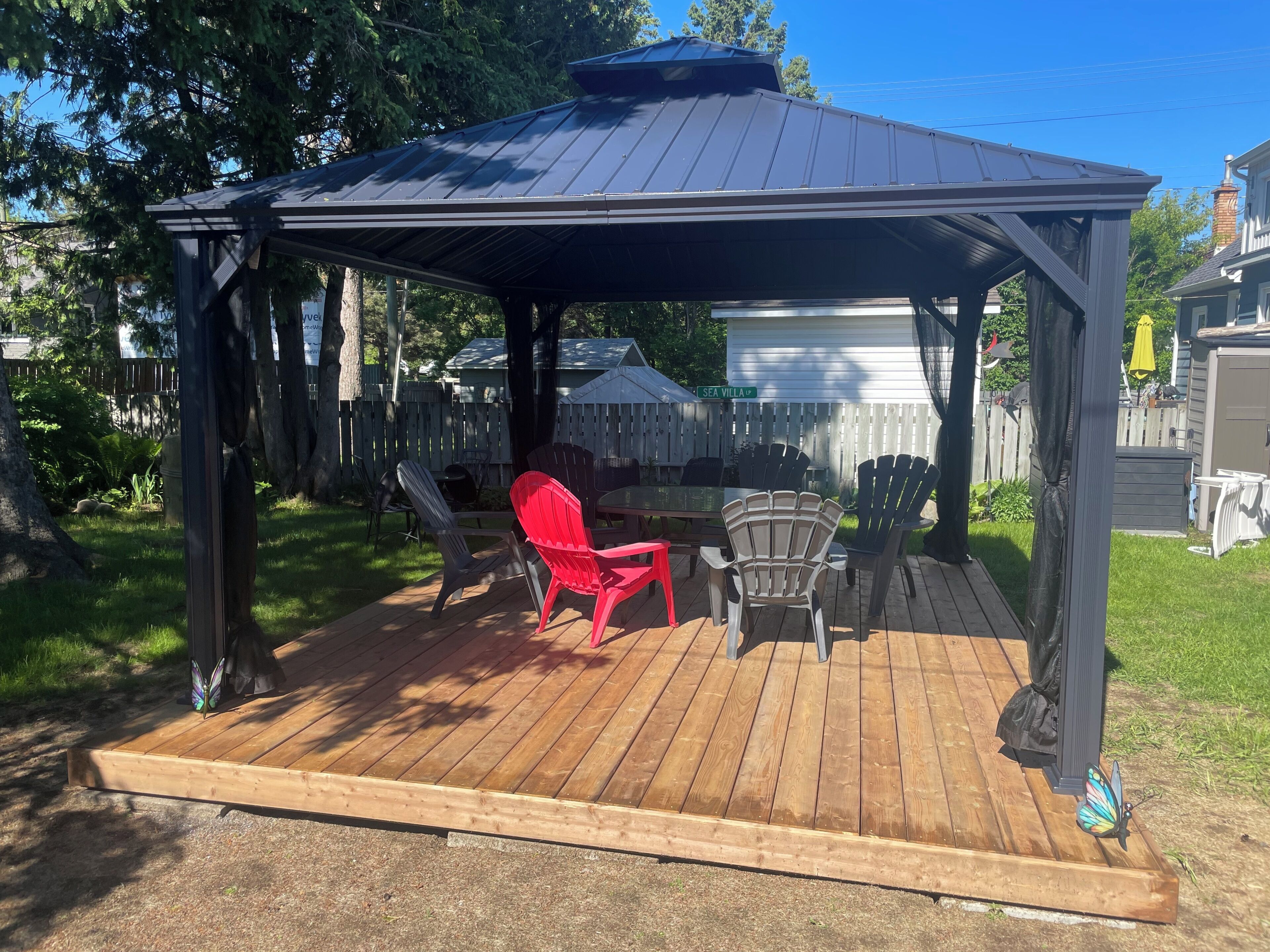 Une terrasse en bois avec un belvédère, des sièges d’extérieur et une vue sur un quartier résidentiel.