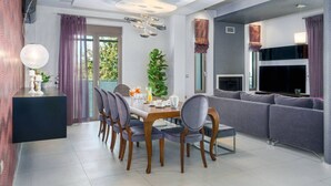 A modern living room with a dining area, a flat-screen TV, and a fireplace.