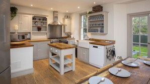 Una cocina con armarios blancos, encimera de madera, estufa y lavavajillas.