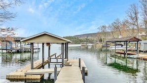 Um cais com um pavilhão coberto, barcos e um lago calmo.