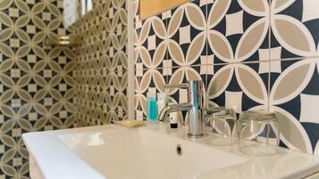 A bathroom with a white sink, a modern faucet, and patterned tiles on the walls.