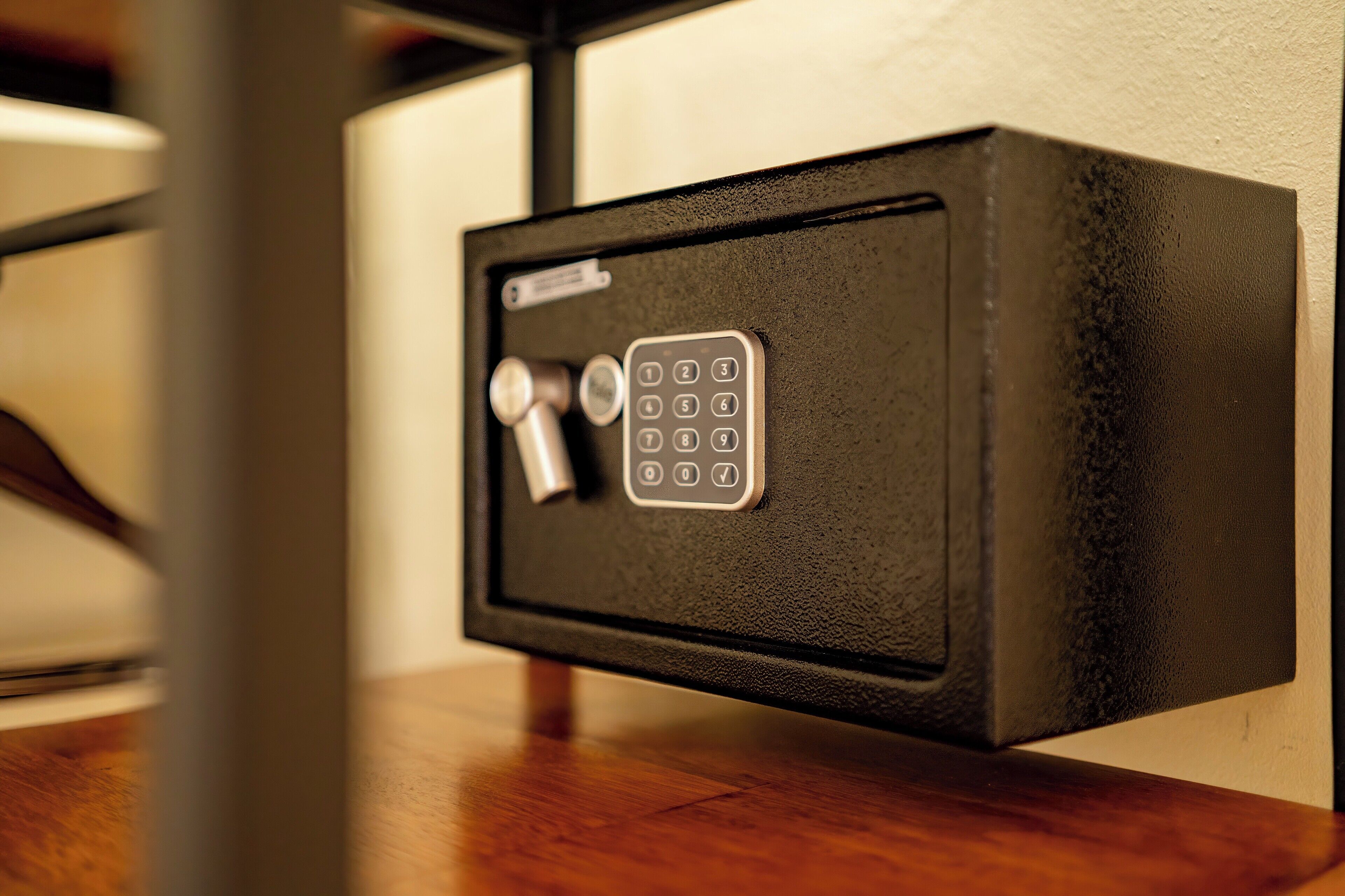 A black safe with a numeric keypad and a keyhole, mounted on a wall.