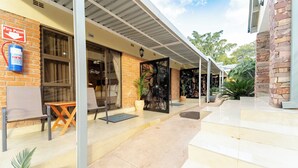 A building with a fire point sign, a fire extinguisher, and a covered outdoor area with steps leading to a door. - The Shrub lodge (Victoria Falls)