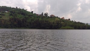 A calm lake with a boat in the foreground. -  LEISURE INN (Muhoza)