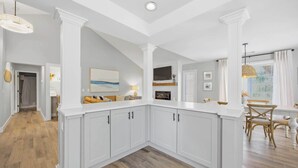 Een moderne keuken met witte kasten, een houten vloer en een eethoek met een tafel en stoelen.