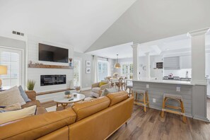 A spacious living area with a sofa, a fireplace, a dining table, and a kitchen with a bar. - Coastal Chic Villa w/ Pool & Beach, Hilton Head (Hilton Head Island)
