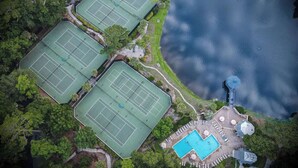Luchtbeeld van een pand met drie tennisbanen, een zwembad en een prieel.