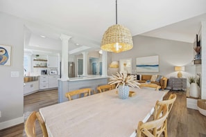 A spacious dining area with a central island, a kitchen in the background, and a living area with a sofa and lamp. - Coastal Chic Villa w/ Pool & Beach, Hilton Head (Hilton Head Island)